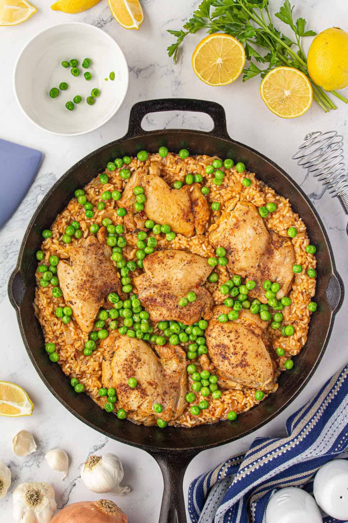 Finished stovetop chicken and rice is topped with frozen peas and a squeeze of fresh lemon.