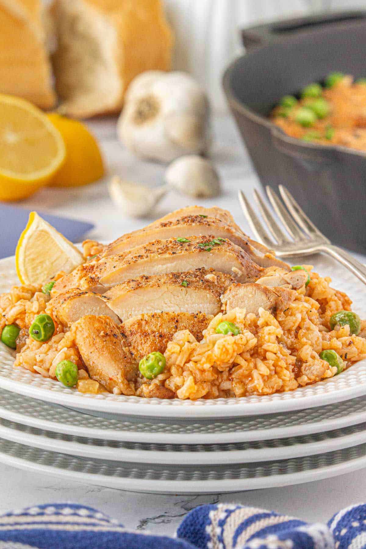 Sliced chicke and rice on a plate. With a skillet in the background.