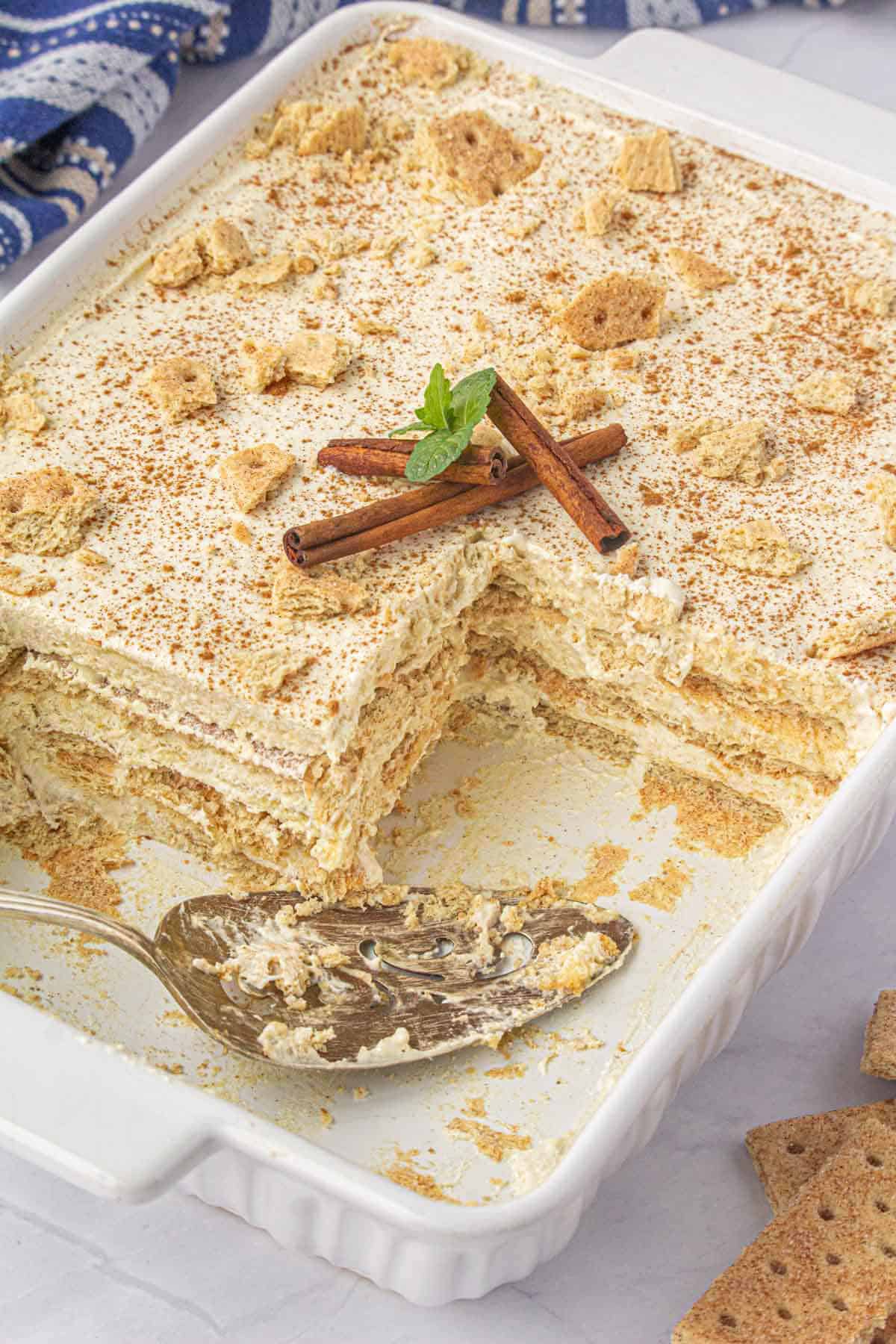 A baking pan filled with pudding graham cracker icebox cake, with a serving spatula.