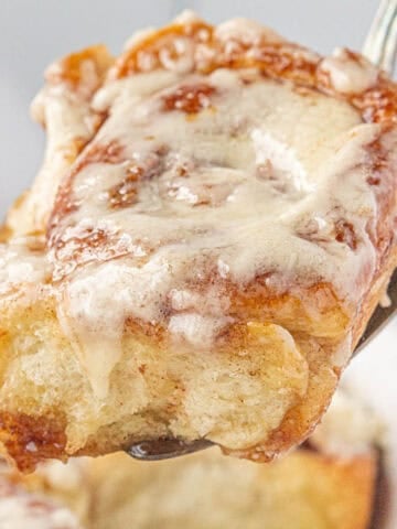 A fresh out of the oven cinnamon roll on a spatula that has been made with frozen bread dough.