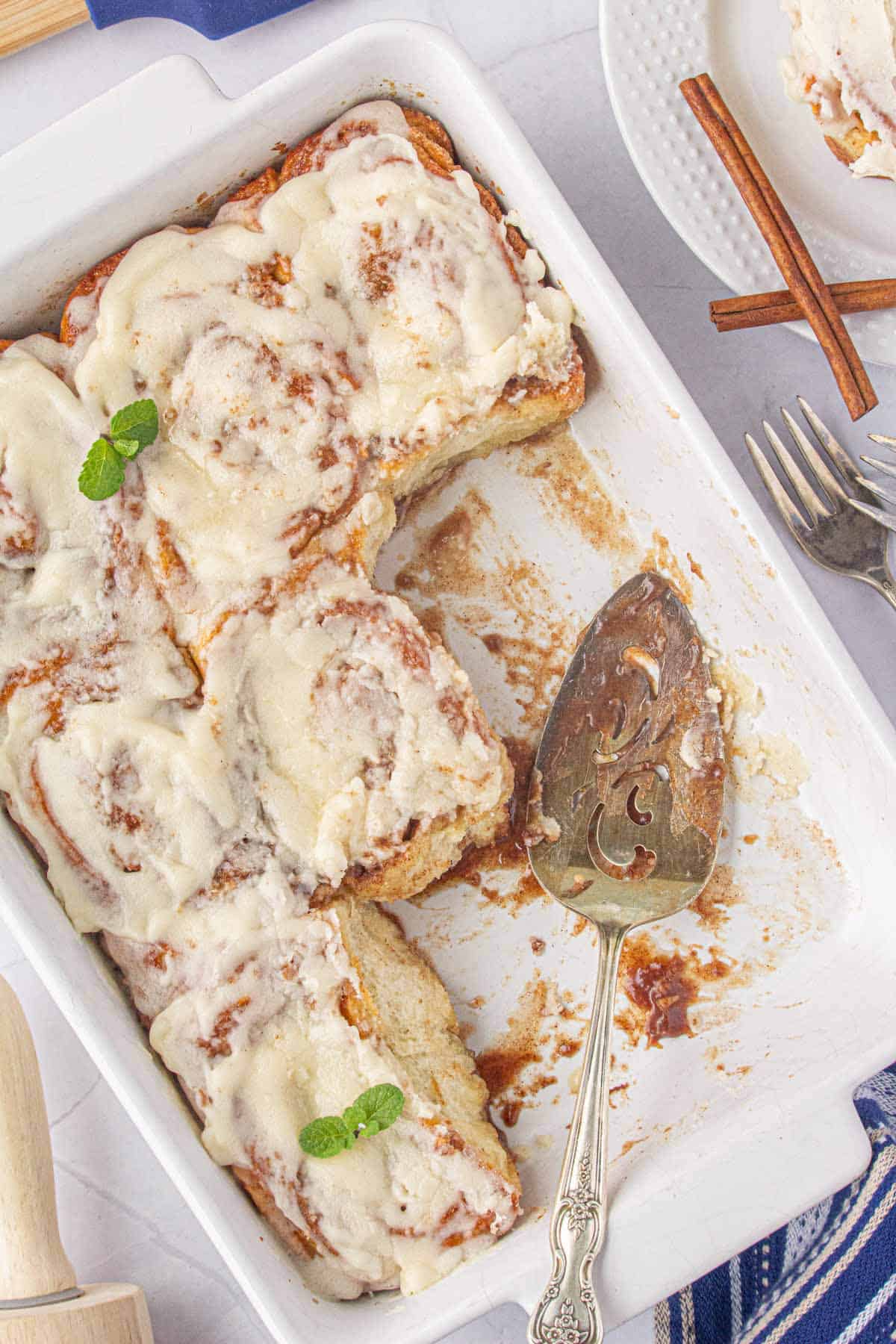 Frozen bread dough cinnamon rolls in a baking dish with a serving spatula.