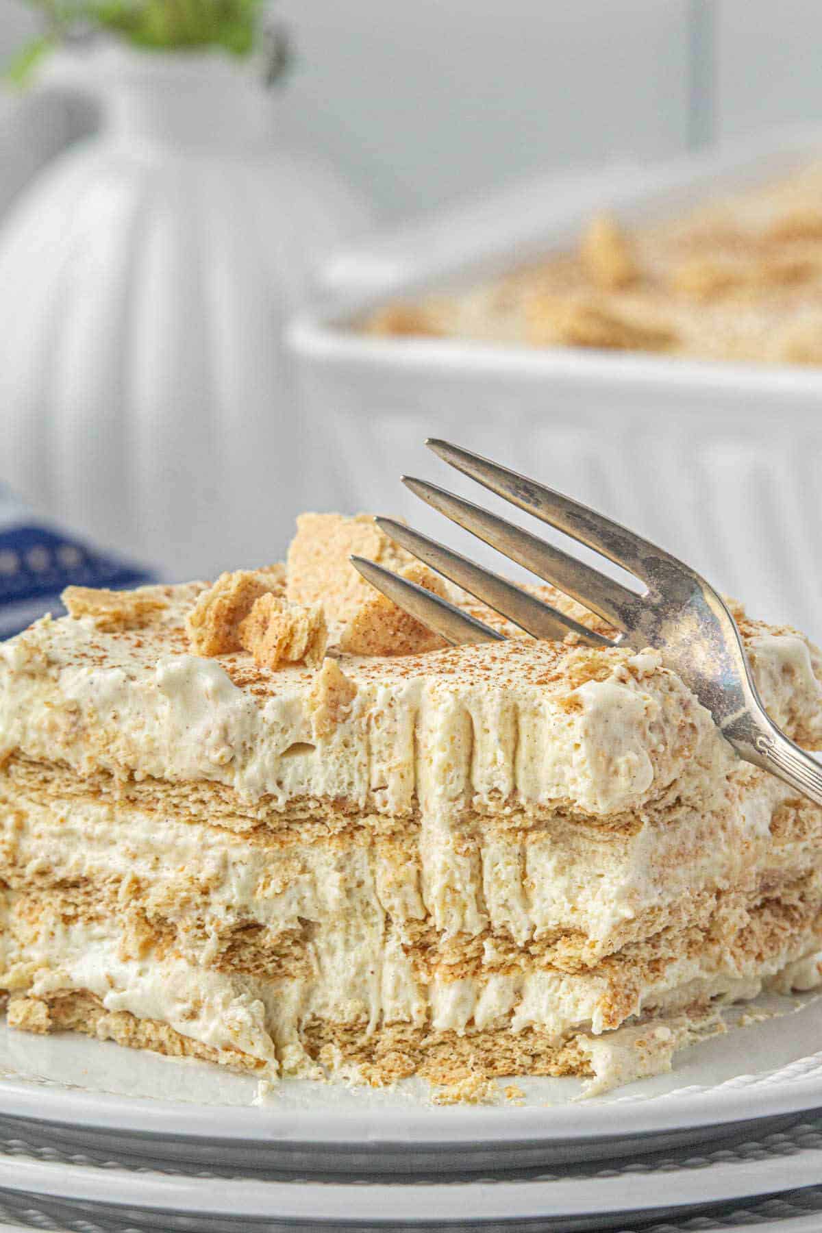 A slice of icebox cake on a plate with a fork taking a bite.