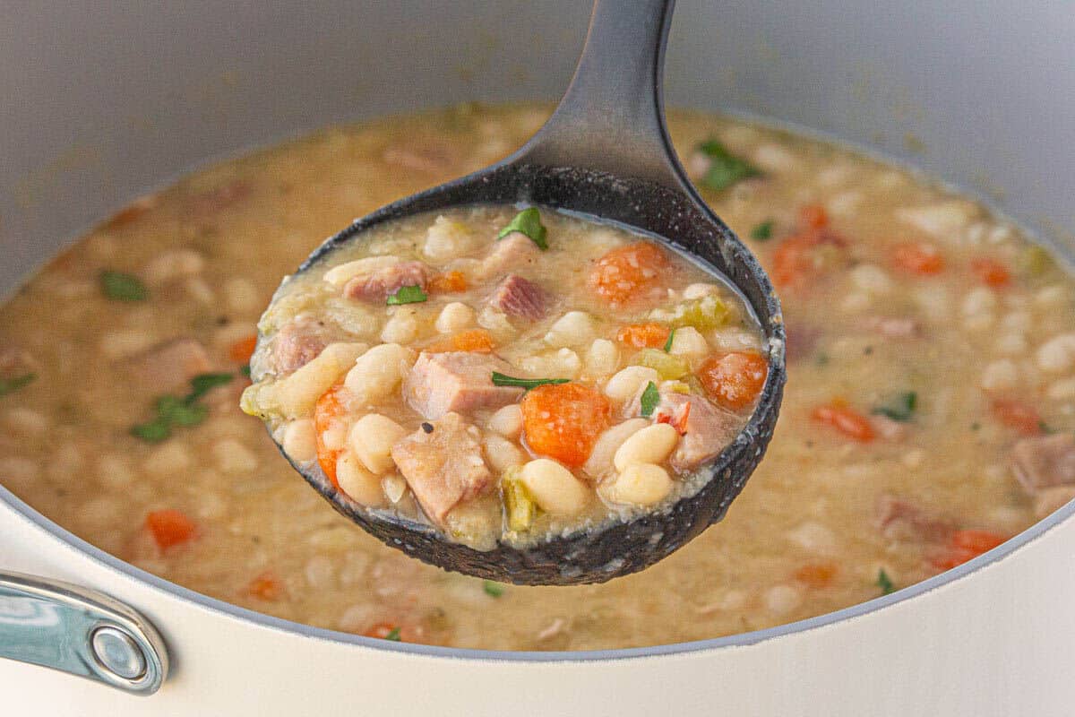 A soup pot with a ladle taking a big scoop.