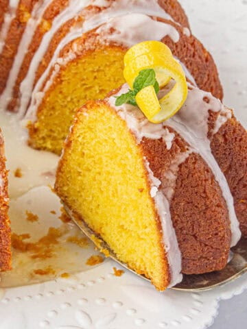 A slice of lemon bundt cake on a white serving platter.