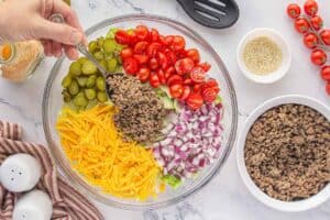 Ground beef added on top of a bed of shredded lettuce, partway through assembling the Big Mac Salad.
