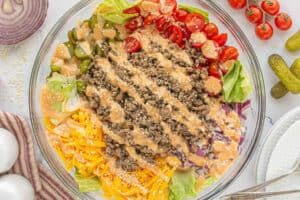 Final step showing the completed salad topped with sesame seeds and creamy dressing, ready to be served.