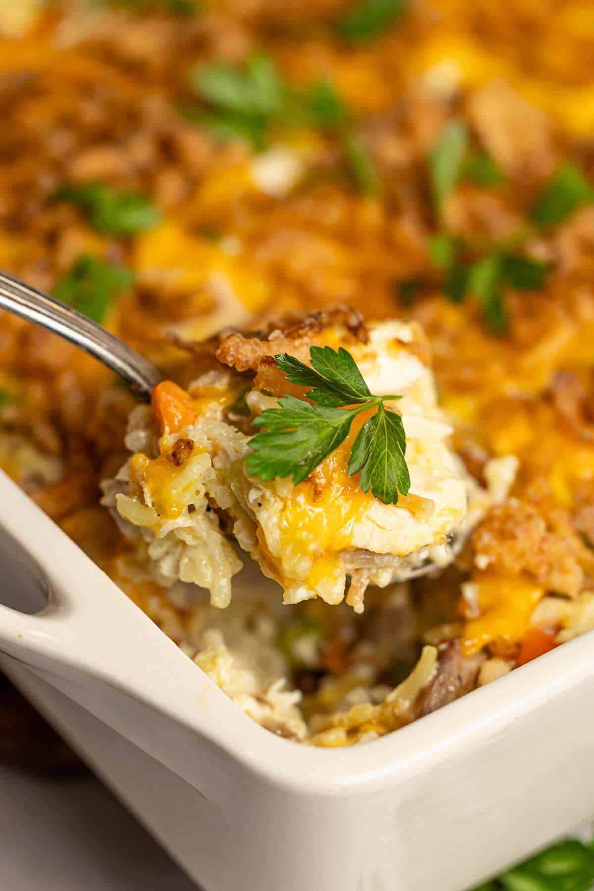 Close-up of baked chicken Rice-A-Roni casserole with golden cheese, crispy onions, and a garnish of fresh parsley.
