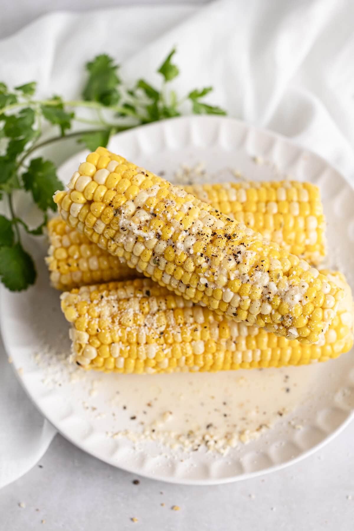 Close-up of buttery corn on the cob stacked on a white plate.