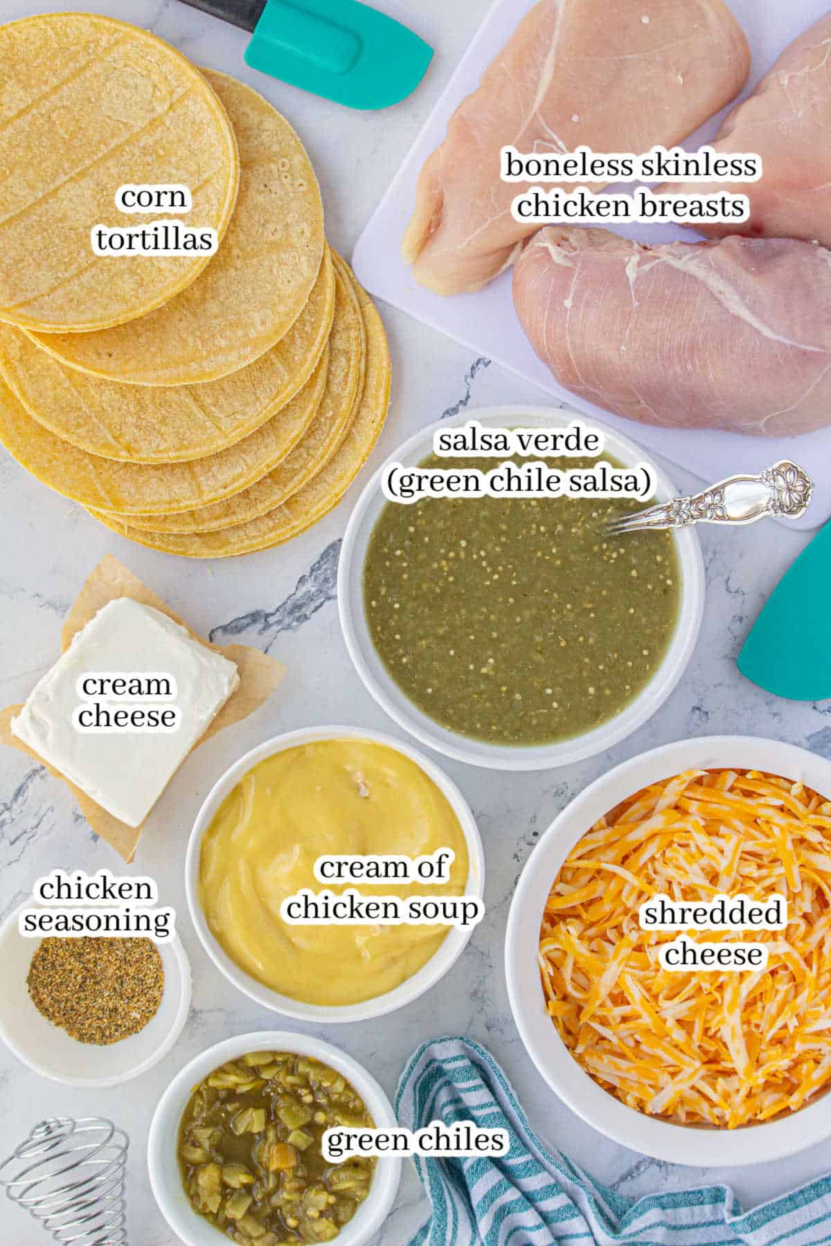 Labeled ingredients displayed on a marble countertop, including corn tortillas, chicken breasts, salsa verde, cream cheese, cream of chicken soup, chicken seasoning, and shredded cheese.