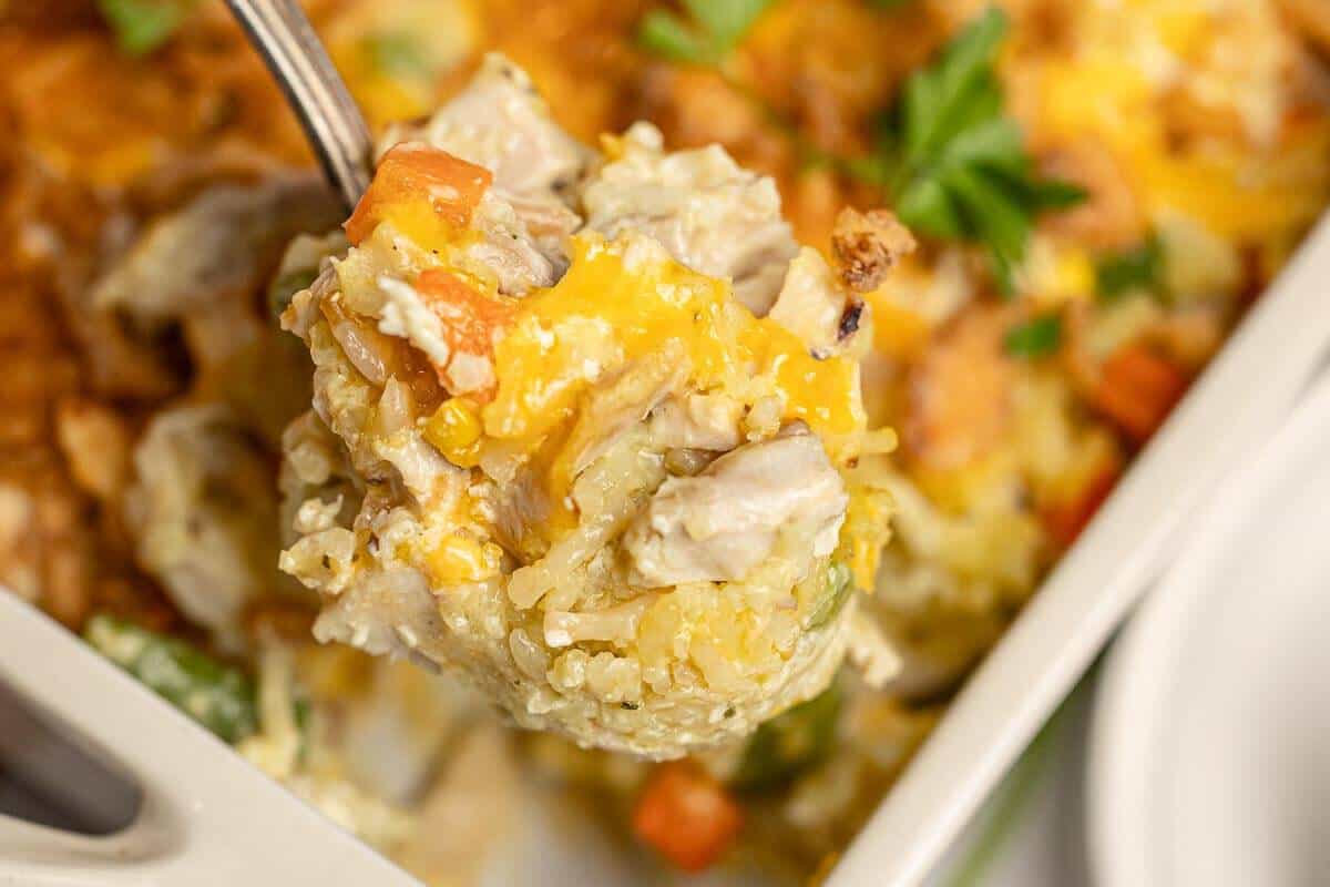 Spoonful of creamy chicken Rice-A-Roni casserole with melted cheddar, vegetables, and tender chicken.