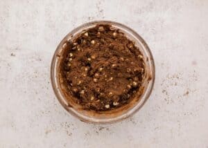 Chocolate cookie dough with visible white and semi-sweet chocolate chips stirred in, ready for scooping.