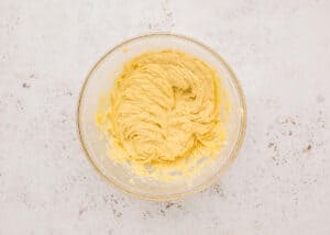 Glass mixing bowl filled with creamy, pale yellow cookie dough after the wet ingredients have been mixed.