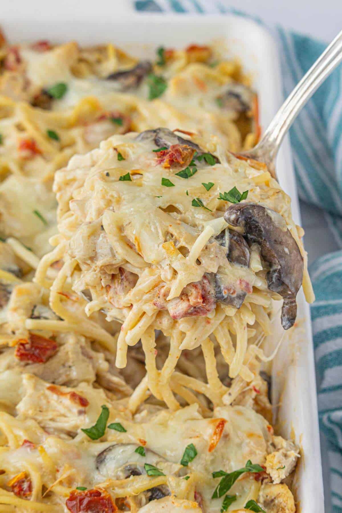 Creamy Angel Chicken Casserole in a baking dish, with a spoon scooping out a large serving.