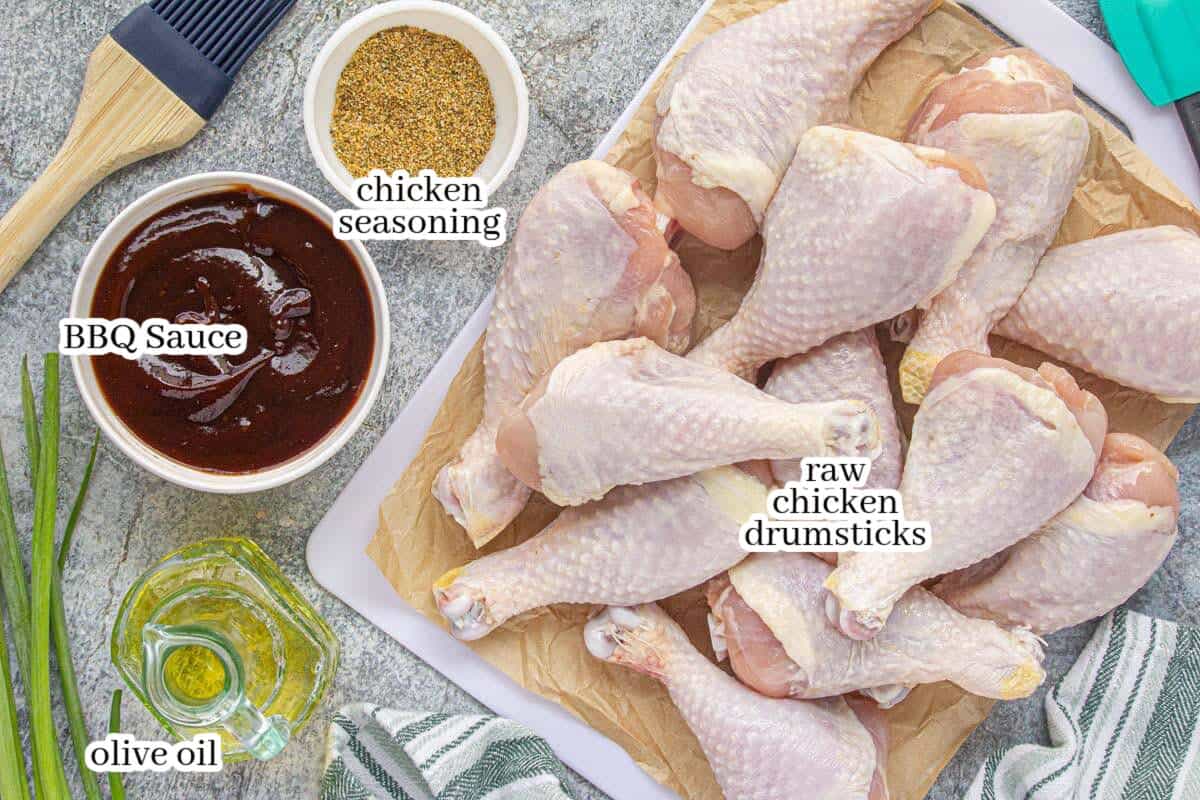 Ingredients to make the baked chicken legs including, bbq sauce, olive oil, chicken seasoning and raw chicken drumbsticks.