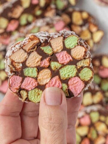 A hand holding a slice of Cathedral Window, with the remaining slices of candy in the background.