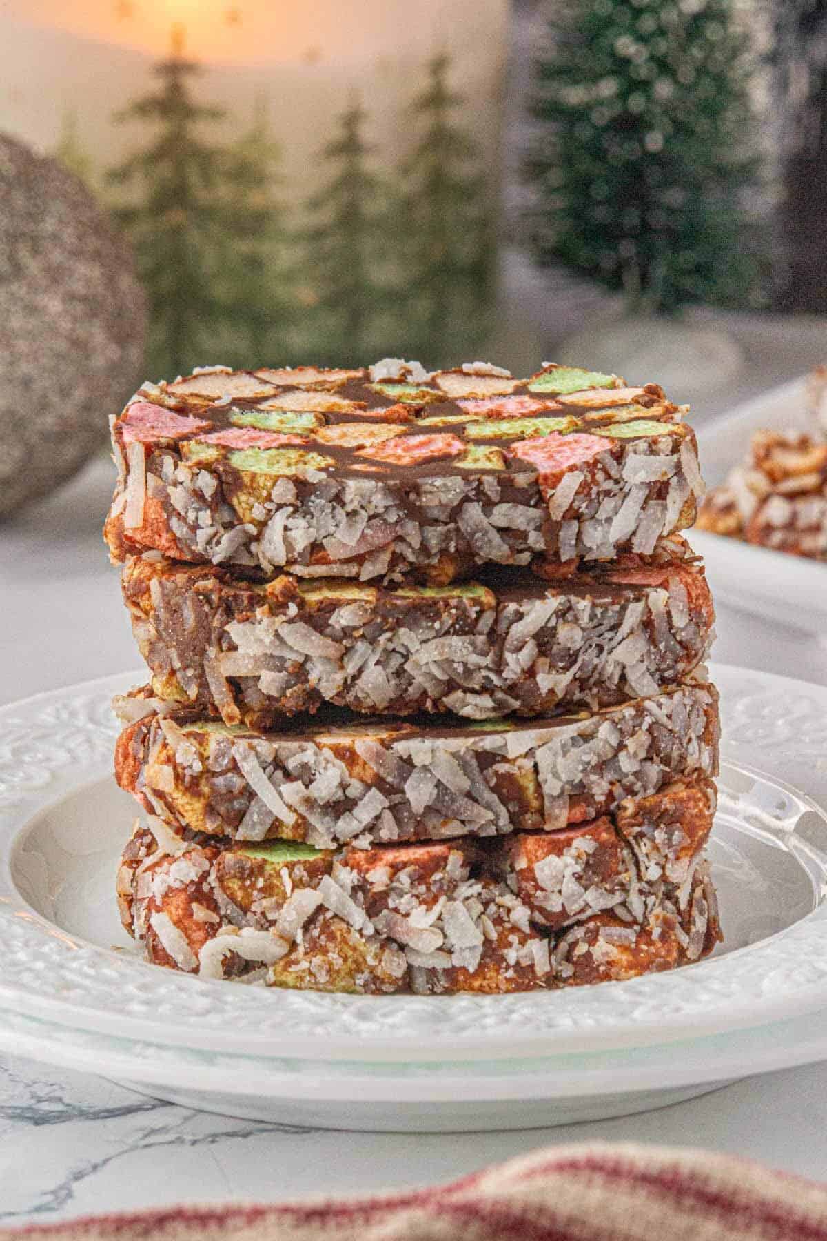 Slices of cathedral candy on a white plate, with Christmas trees and holiday decor in the background.
