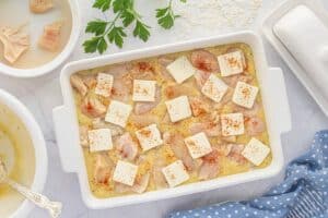 Chicken and rice casserole topped with pats of butter and a sprinkle of paprika, arranged evenly before going into the oven.
