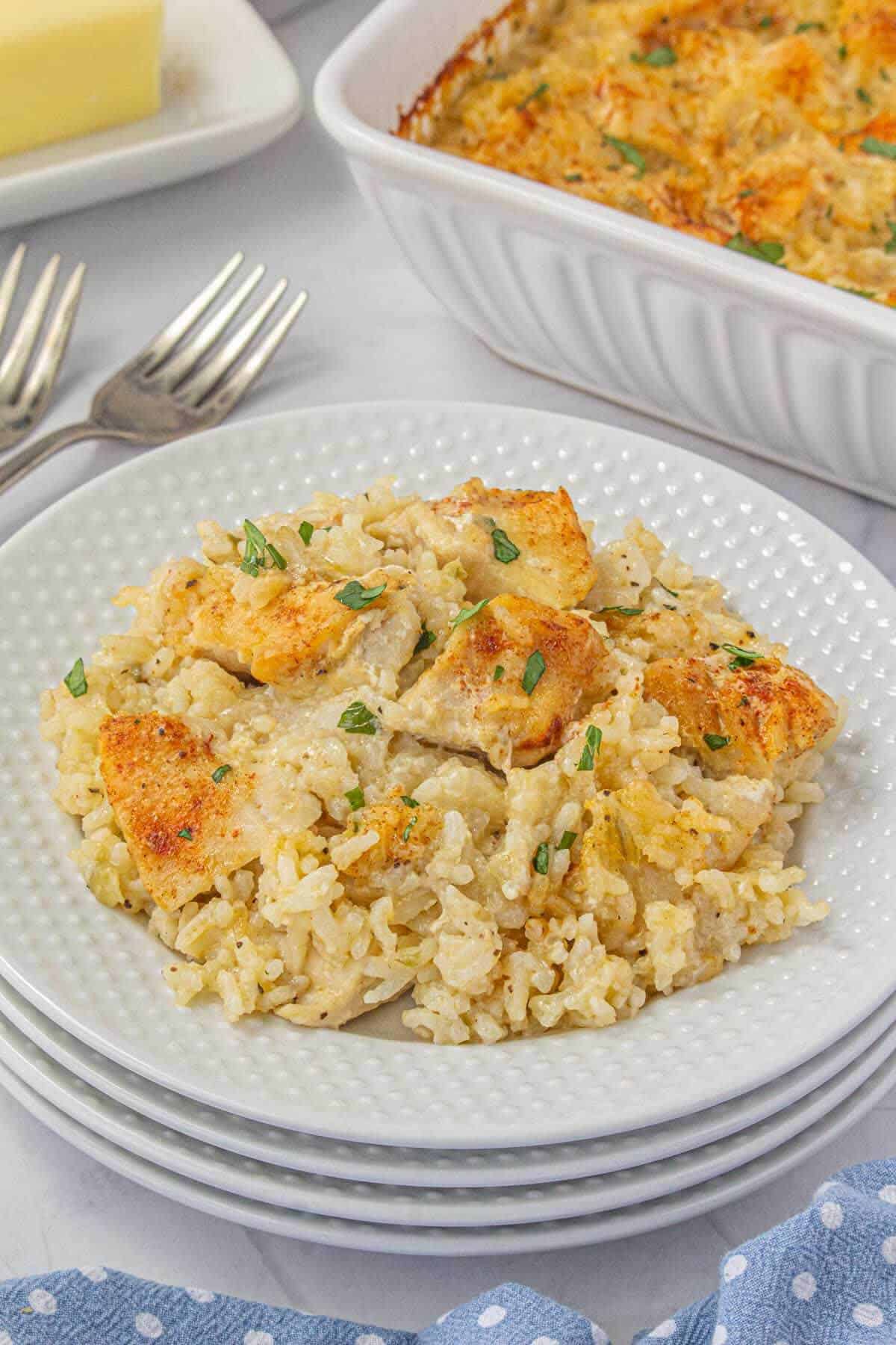 A generous portion of creamy baked chicken and rice on a white textured plate, garnished with parsley.