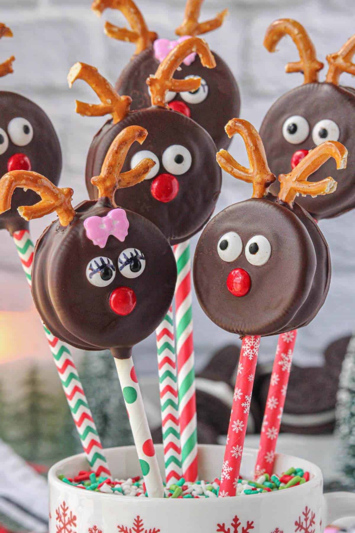 Decorated Reindeer Oreo Cookies displayed upright on holiday straws.