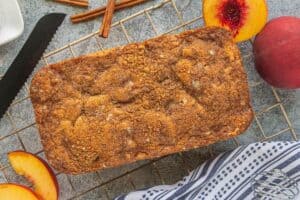 Baked peach quick bread cooling on a wire rack, golden brown with a crisp crumble topping.