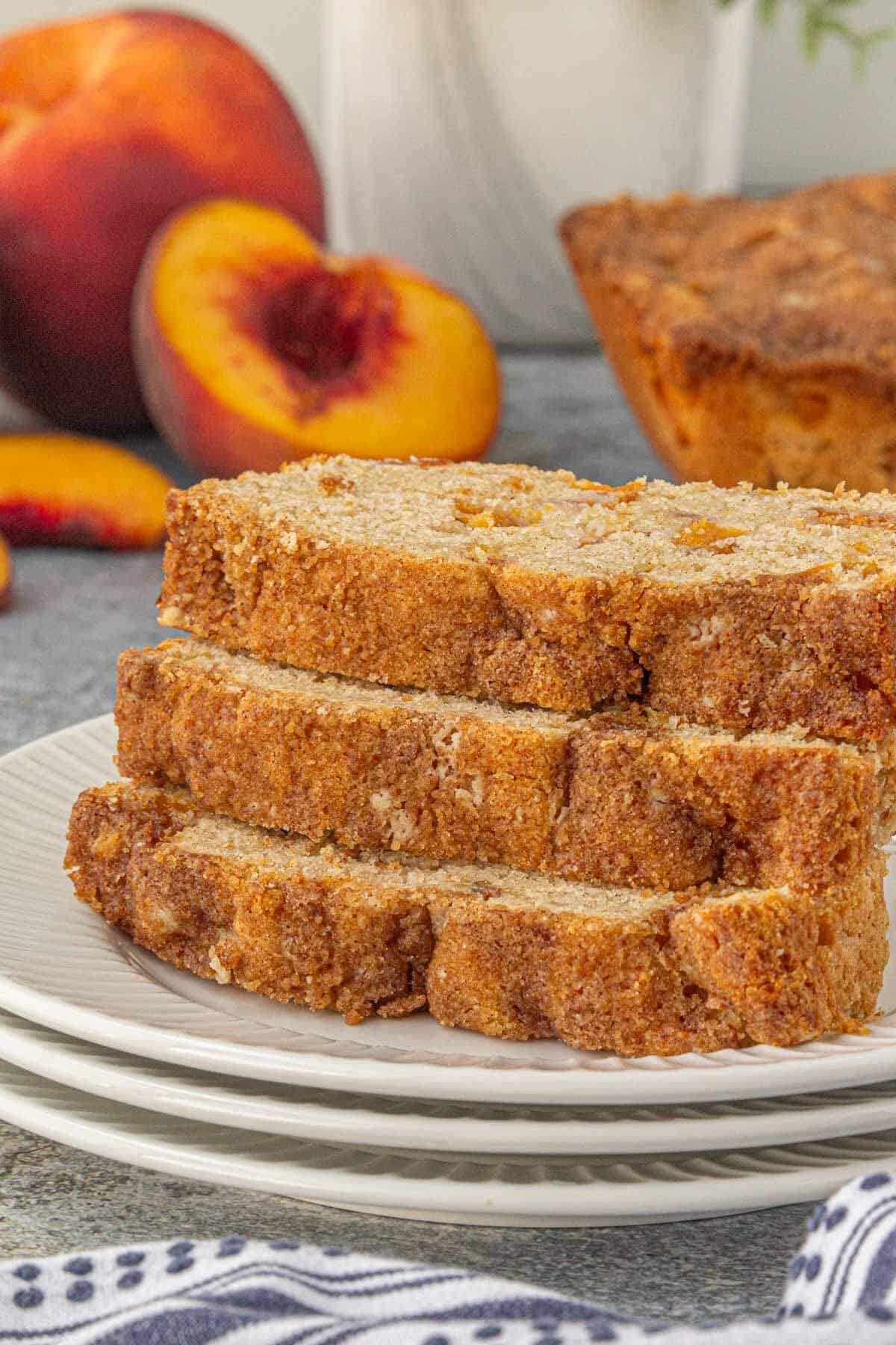 Close-up of peach quick bread slices with a tender crumb and baked peach pieces throughout the loaf.