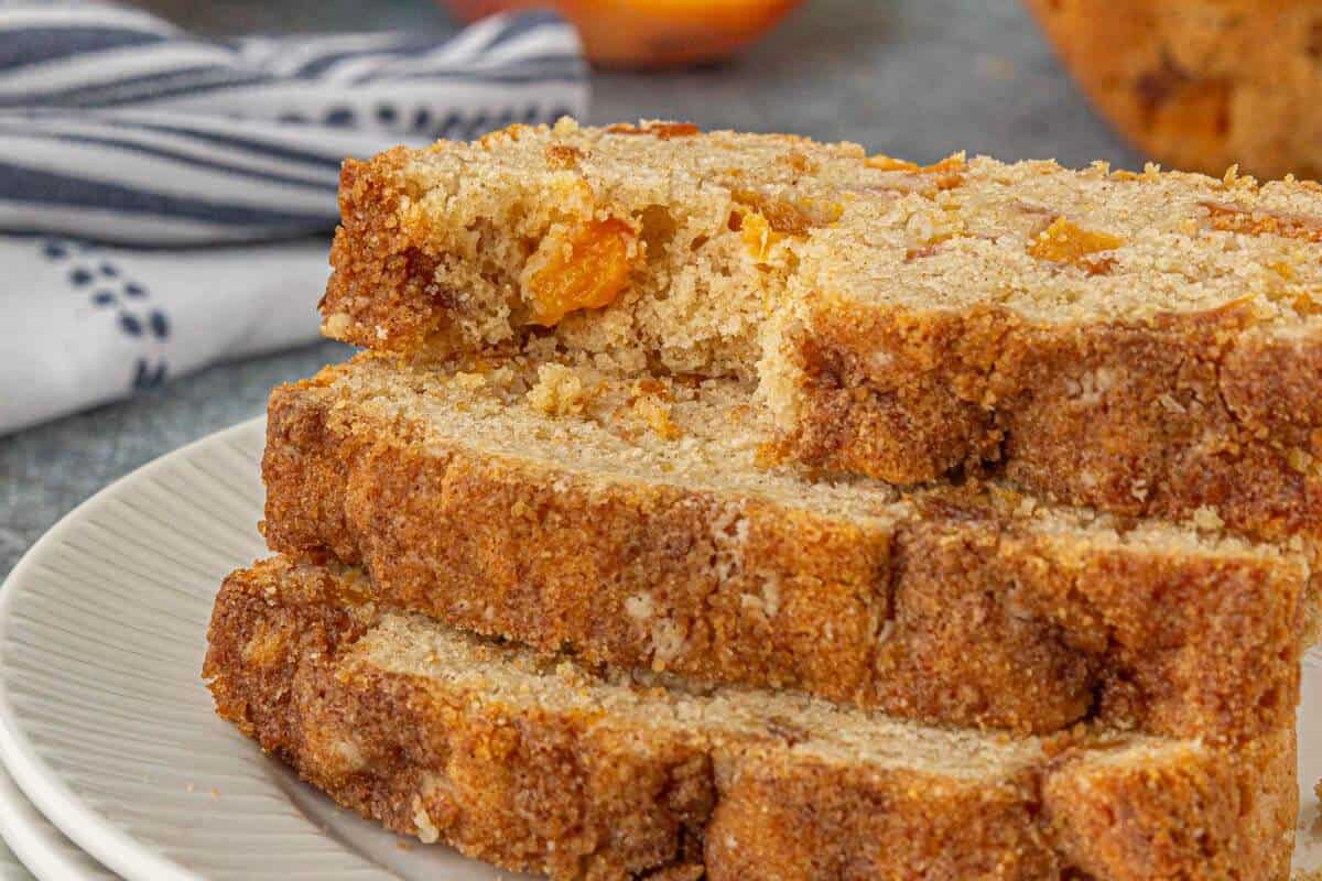 Sliced Peach bread on a plate. The top slice has a bite taken out of it.