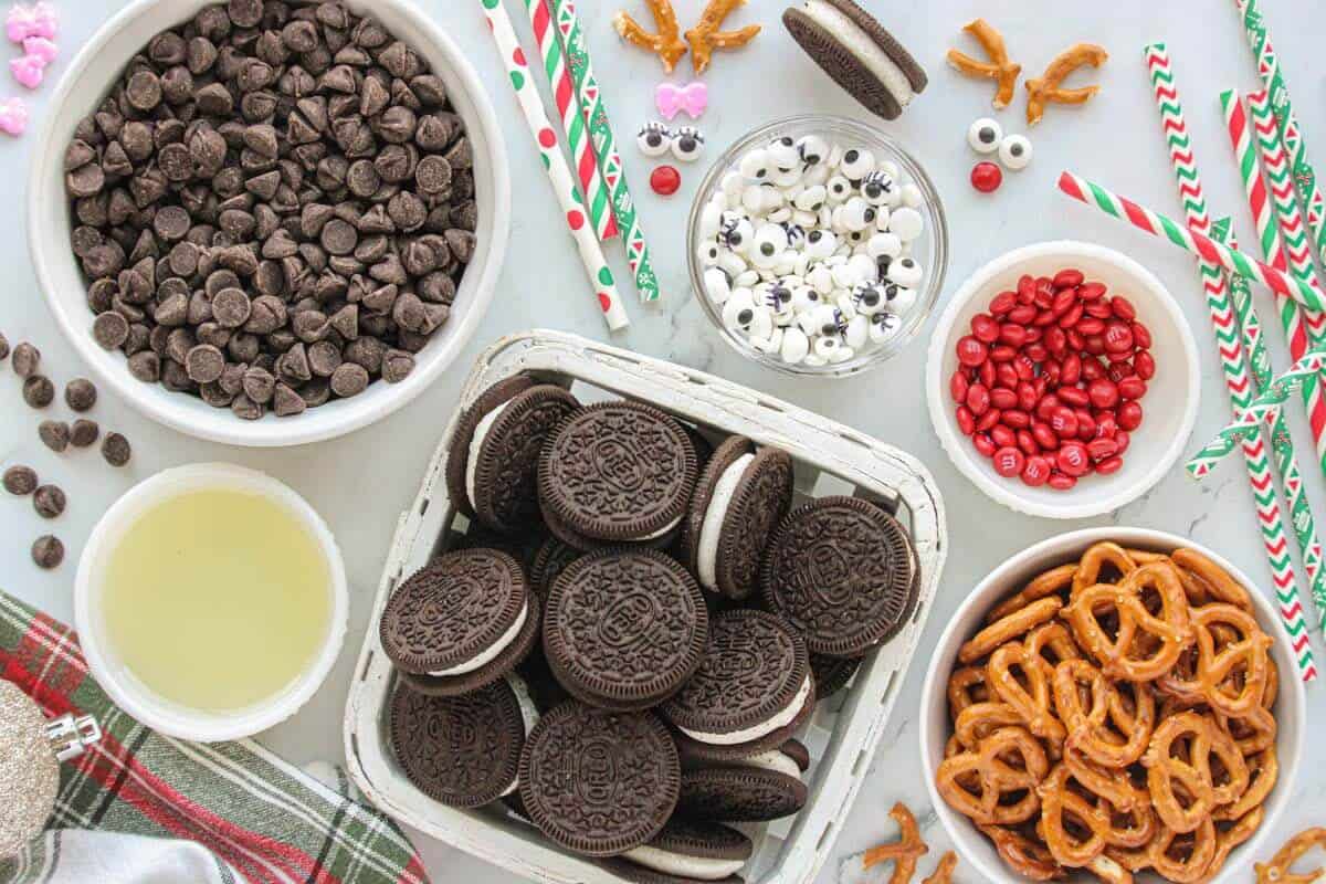 Oreos, vegetable oil, mini pretzels, mini m&m's, chocolate, paper straws and candy eyeballs. All of the ingredients needed to make the holiday candy recipe.