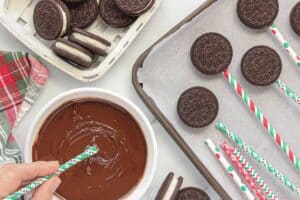 Paper straw being dipped into melted chocolate.