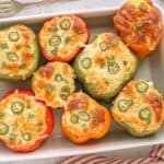 Baking dish filled with colorful stuffed bell peppers topped with cheesy cornbread and jalapeño slices, garnished with fresh cilantro for a Tex-Mex twist.