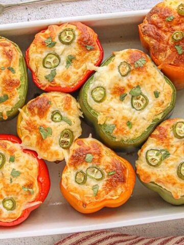 Baking dish filled with colorful stuffed bell peppers topped with cheesy cornbread and jalapeño slices, garnished with fresh cilantro for a Tex-Mex twist.