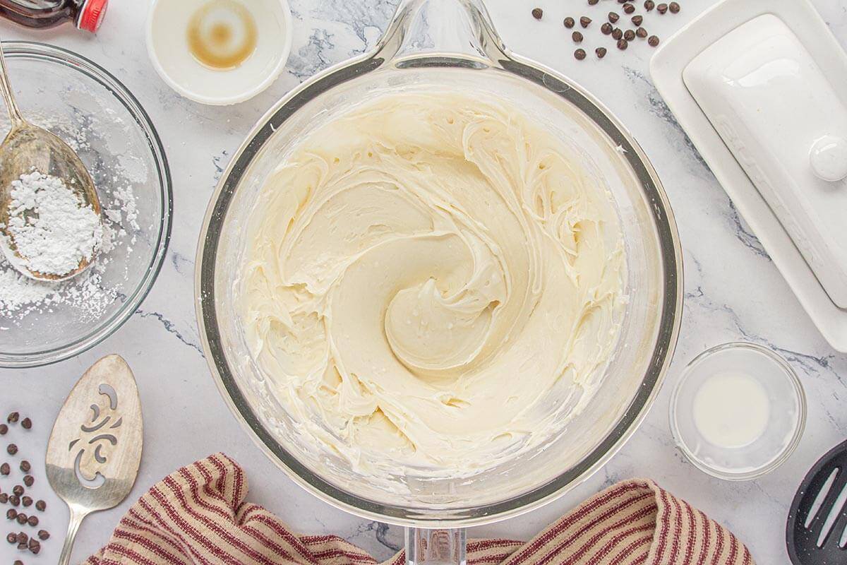 Creamy vanilla frosting in a glass mixing bowl.