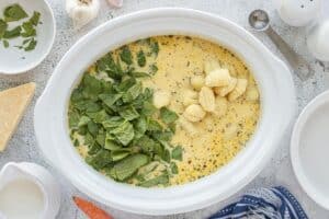 Fresh spinach and uncooked gnocchi added to the creamy chicken soup mixture in a slow cooker.