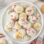 Gingersnap Truffles on a white platter, ready to eat and enjoy. Truffles are decorated with holiday sprinkles and gingersnap crumbs.