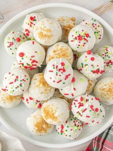 Gingersnap Truffles on a white platter, ready to eat and enjoy. Truffles are decorated with holiday sprinkles and gingersnap crumbs.
