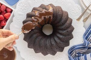 Chocolate glaze being drizzled over a chocolate olive oil Bundt cake