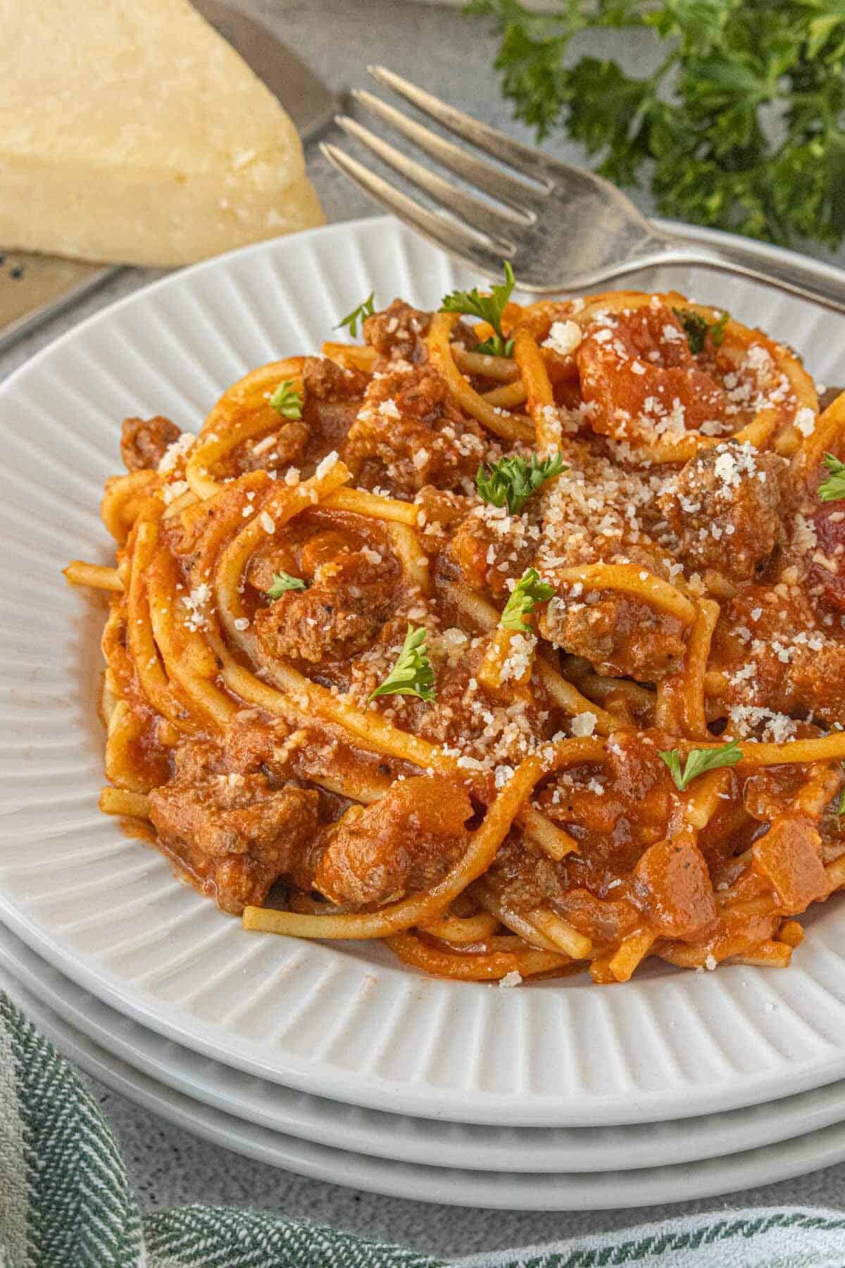 Plated serving of spaghetti hamburger helper topped with grated cheese and fresh parsley on a white plate.