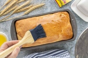 Freshly baked loaf of sandwich bread brushed with melted butter for a soft golden crust.