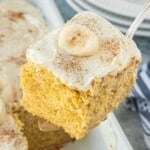 Close-up of banana cake showing soft texture and creamy frosting.