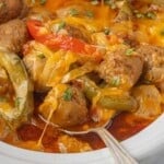 Slow cooker filled with saucy Burrito meatballs, with peppers, onions, and topped with melted cheese.