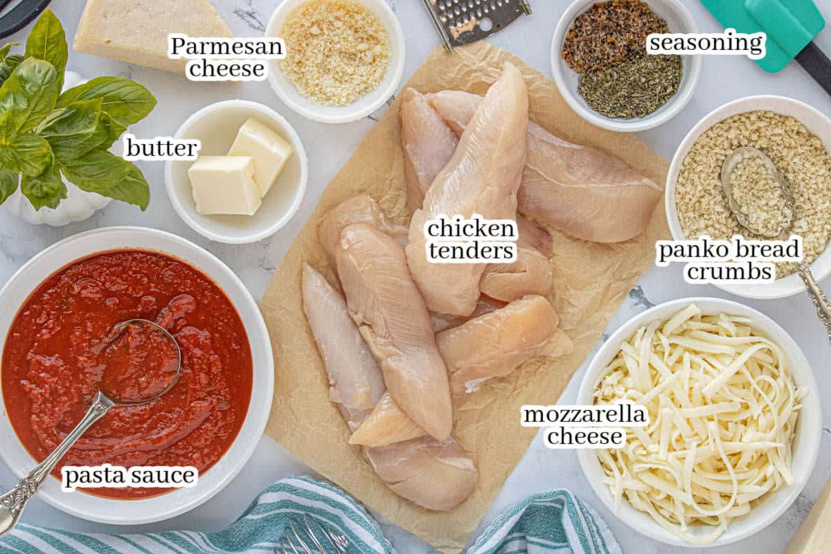 All of the ingredients to make crockpot chicken parmesan on a counter top, including chicken tender, mozzarella and parmesan cheese, panko bread crumbs, butter and seasoning.