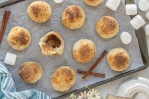 Golden baked rolls on a sheet pan with one opened to reveal a hollow center.