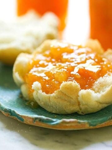 Homemade jam on a toasted english muffin on a blue plate.