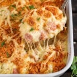 Chicken cordon bleu casserole with creamy chicken and ham, melted Swiss cheese, and a buttery cracker topping being lifted from a baking dish with a spoon.