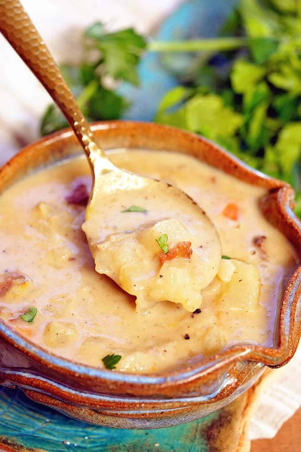 Creamy clam chowder with bacon, potatoes, and clams in a rustic bowl with a spoon.