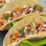 Soft tacos filled with chicken tinga topped with diced onion, cilantro, and crumbled cheese.