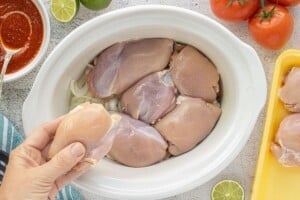 Raw chicken thighs placed over sliced onions in a slow cooker.