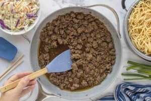 Cooked ground beef simmering in a savory sauce in a large skillet.