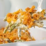 Close-up of asparagus casserole showing tender asparagus in a rich sauce with a crunchy cheese cracker topping being lifted from the casserole dish with a spoon.