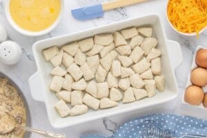 Cut refrigerated biscuit dough into bite-sized pieces and arrange evenly in a greased casserole dish for biscuits and gravy casserole.