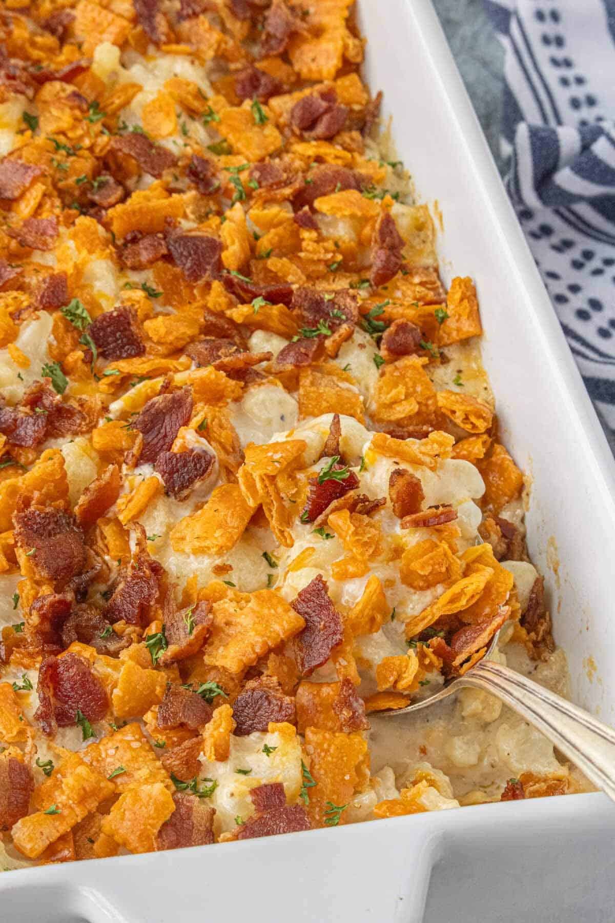 Close-up of baked cauliflower casserole with crispy bacon and cracker topping in a white casserole dish.